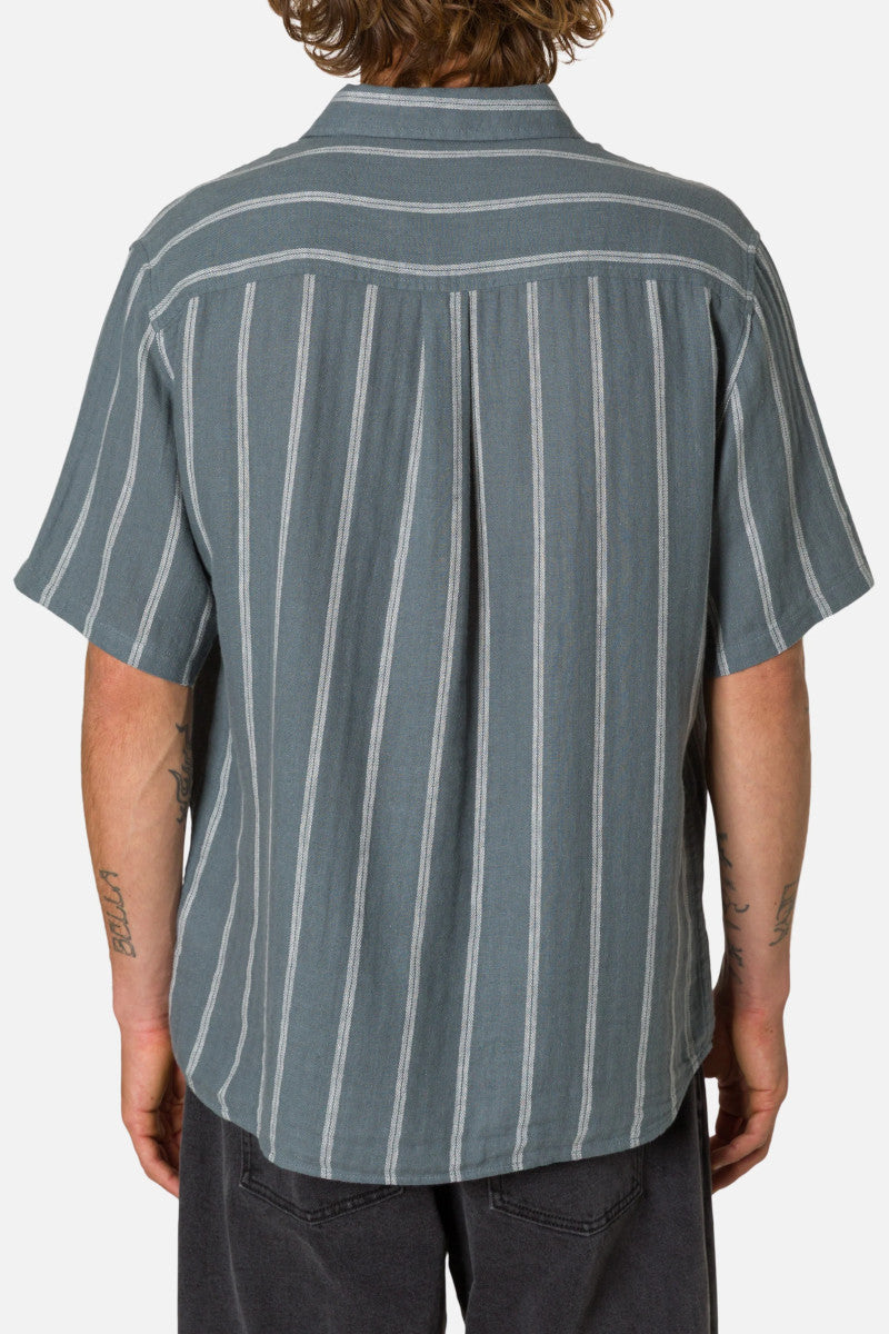 Person wearing a short-sleeve button-up shirt with vertical stripes on a plain background