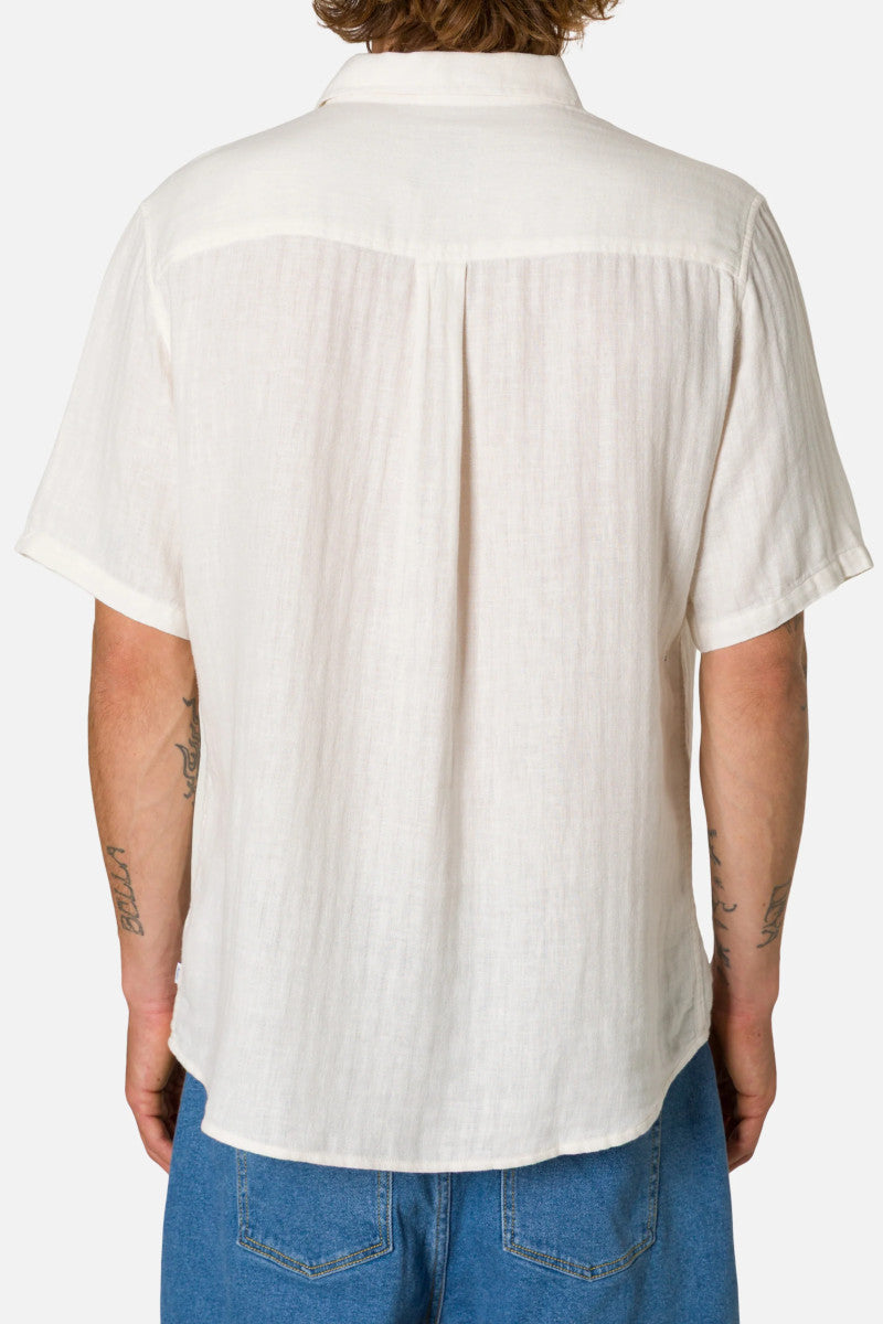 Person wearing a white short-sleeve button-up shirt and blue pants on a white background