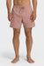 A man standing and posing in a pair of rose pink boardshorts with a side pocket, featuring an elastic waist closure.