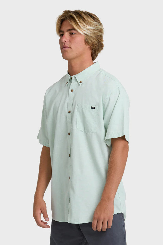 Man wearing a solid, light green short-sleeve button-up collared shirt on a white background