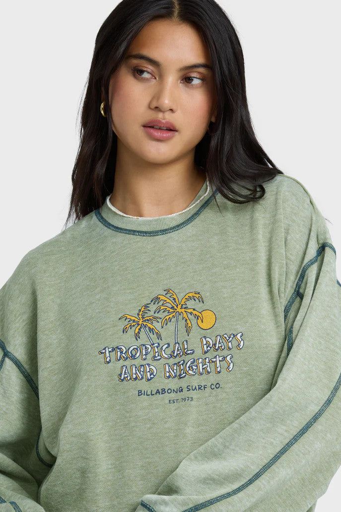 Woman wearing a green sweatshirt with a tropical design and text.