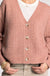 Woman wearing a pink cardigan, white shirt, and beige pants on a white background