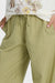 Green striped pants worn with a white sweatshirt featuring floral designs.