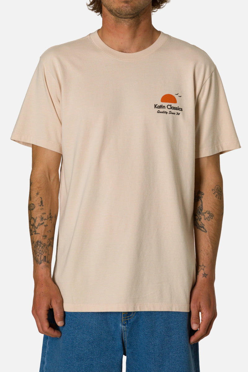 Person wearing a beige t-shirt with a logo on a white background