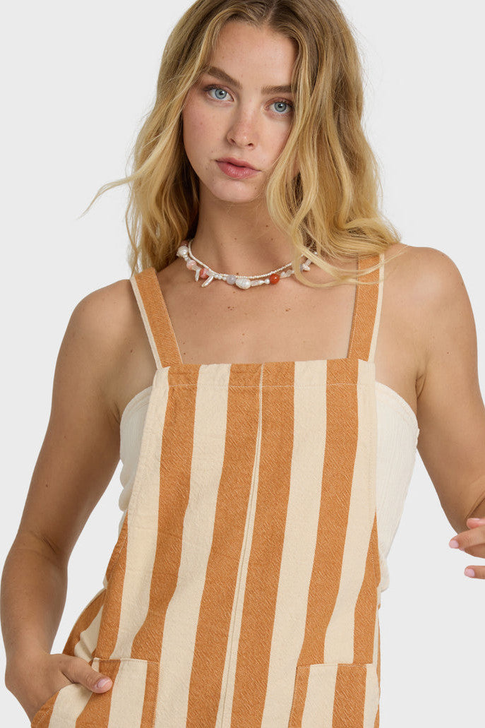 Woman wearing a striped overall romper with a plain background