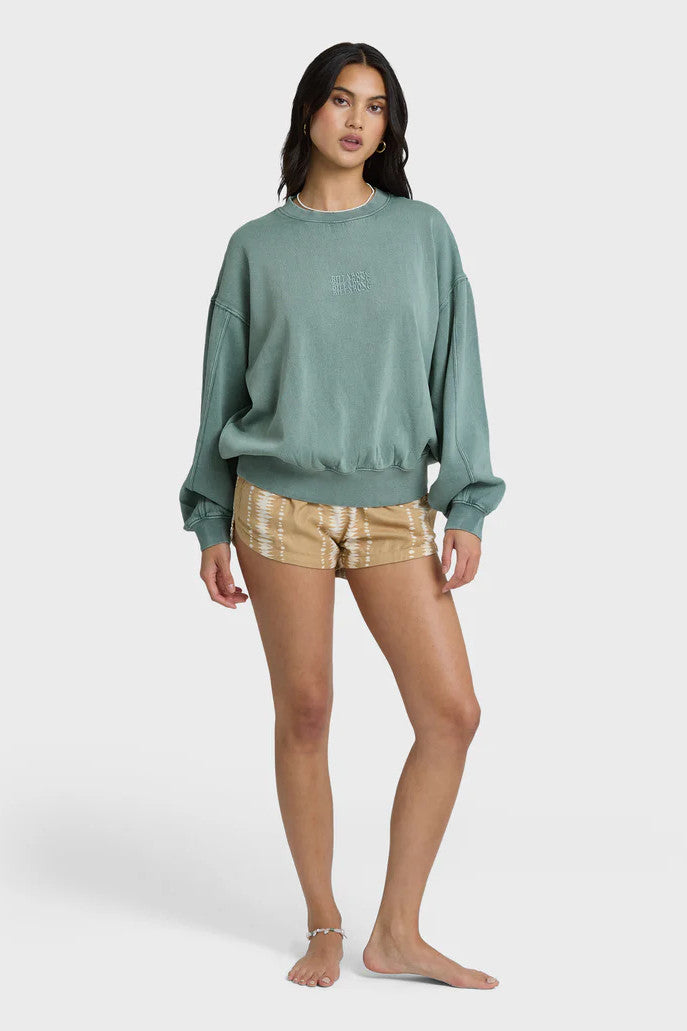 Woman wearing a blue-green sweatshirt with a tonal logo on a white background