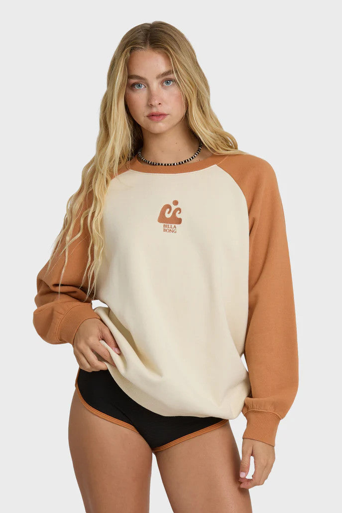 Woman wearing a brown and beige sweatshirt with a wave logo on a white background