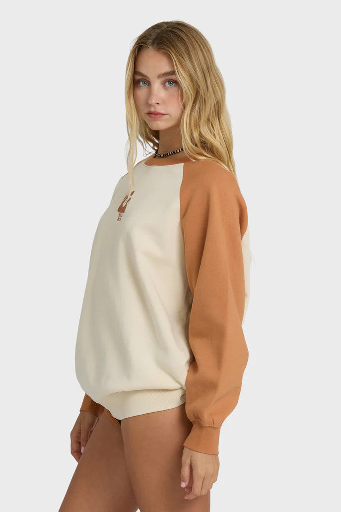 Woman wearing a brown and beige sweatshirt with a wave logo on a white background