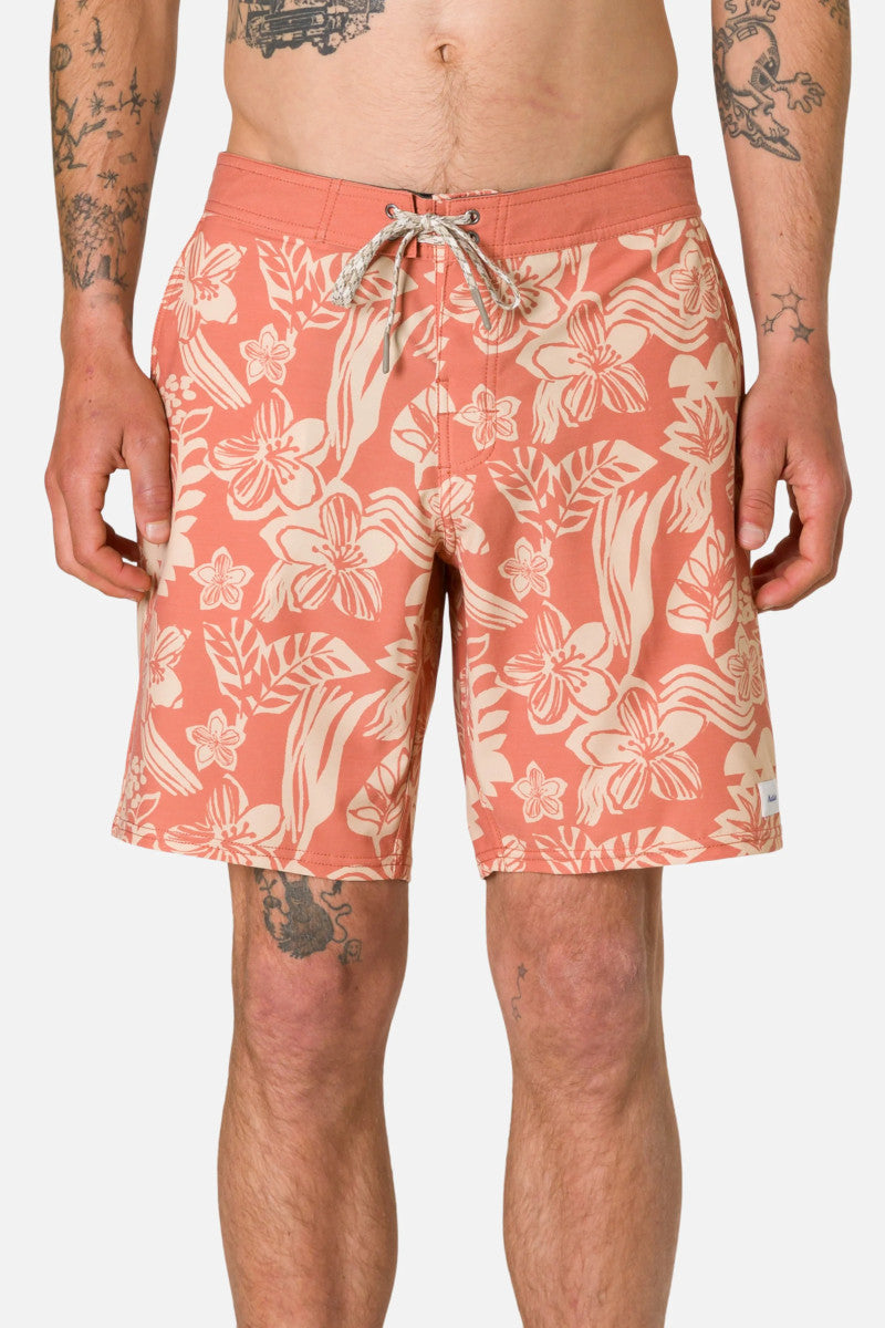 Person wearing coral floral shorts on a plain background