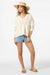 Woman wearing a cream sweater, denim shorts, and a straw hat on a white background