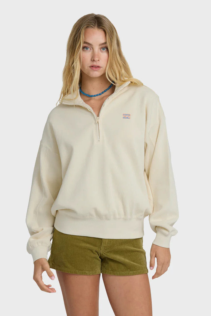 Woman wearing a beige fleece pullover with a brand logo on a white background