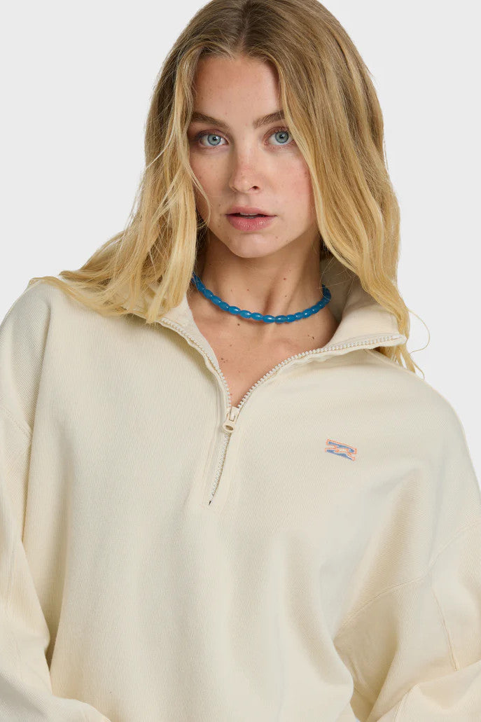 Woman wearing a beige fleece pullover with a brand logo on a white background