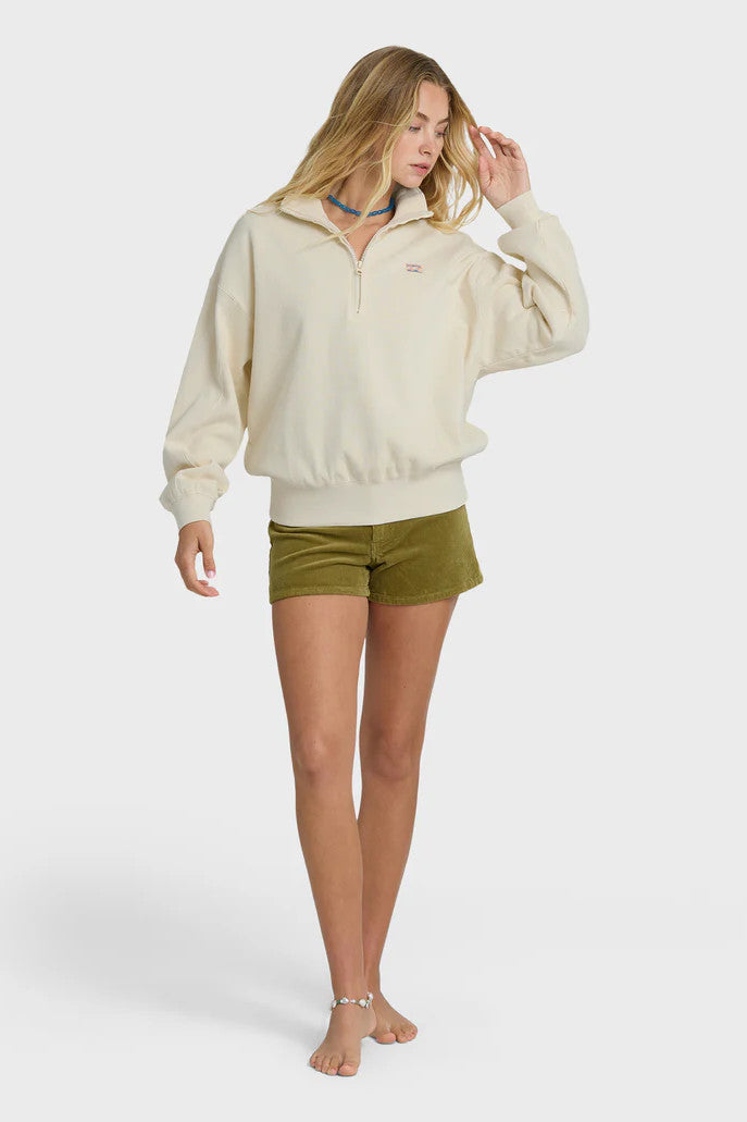 Woman wearing a beige pullover and green shorts on a white background