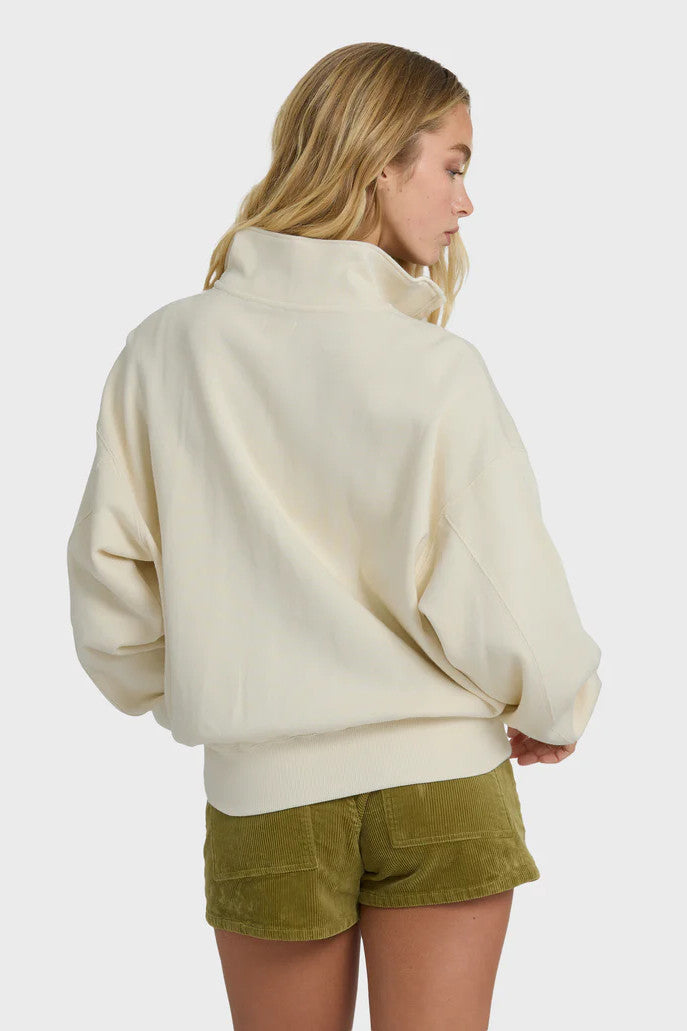 Woman wearing a cream sweater and green shorts on a white background