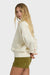 Woman wearing a cream sweater and green shorts on a white background