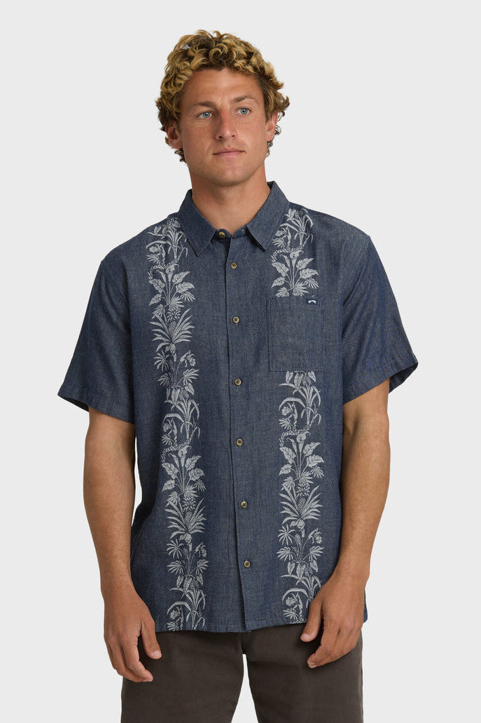Man wearing a dark blue shirt with floral patterns on a white background
