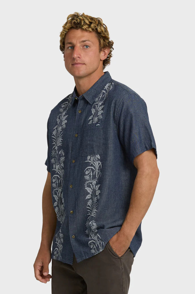 Man wearing a dark blue shirt with floral patterns on a white background