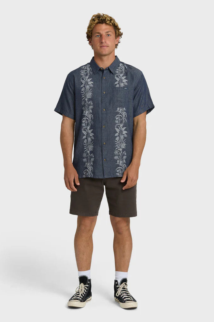 Man wearing a dark blue shirt with floral patterns on a white background