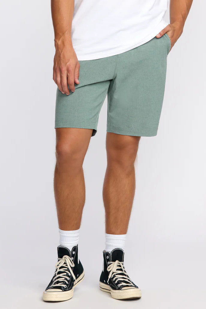 Person wearing green shorts and black sneakers on a white background