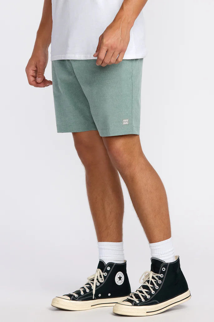 Person wearing green shorts and black high-top sneakers on a white background