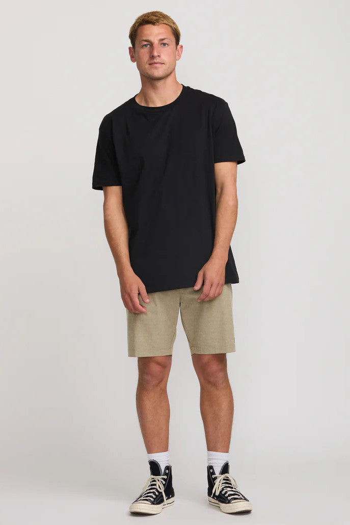 Man wearing a black t-shirt, beige shorts, and black high-top sneakers on a white background