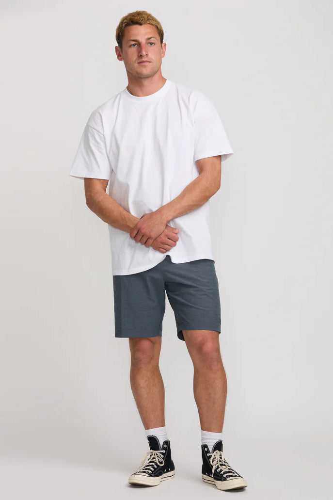 Man wearing a white t-shirt and navy shorts on a plain background