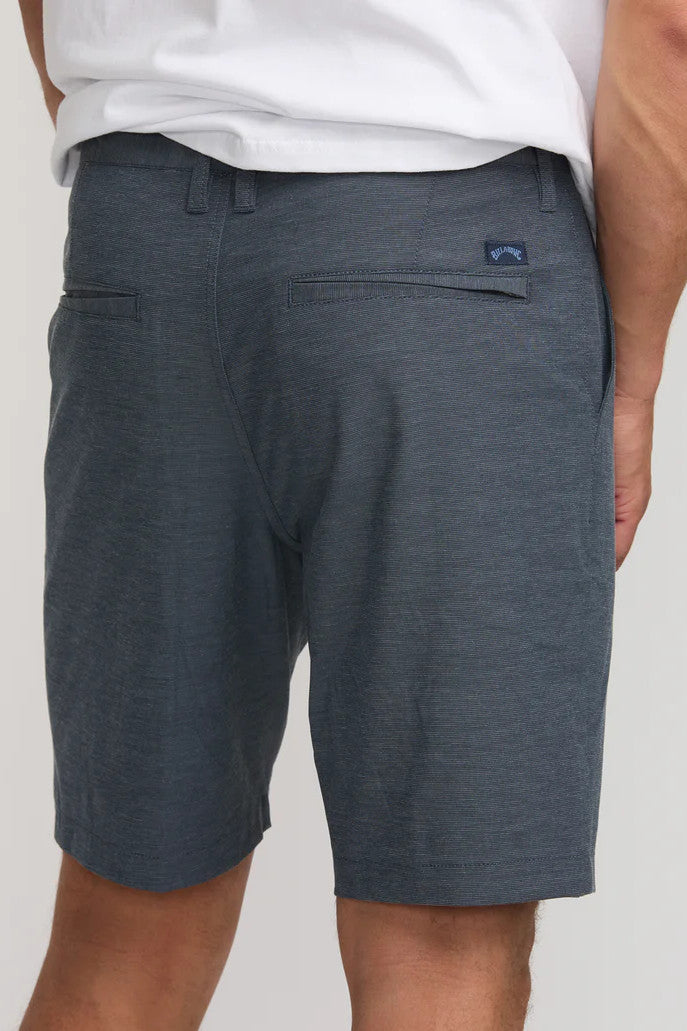 Person wearing navy shorts with a visible brand logo on a light gray background