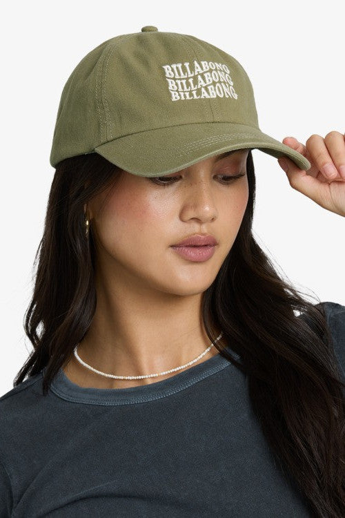 Woman wearing a green baseball cap with a white Billabong logo