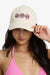 Woman wearing a beige cap with shell designs and a pink bikini top on a white background