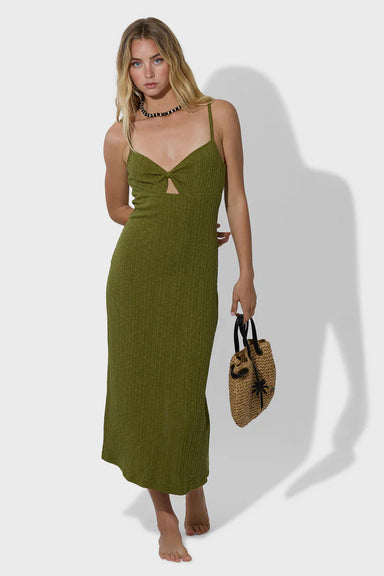 Woman wearing a green dress holding a straw bag on a white background