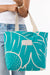 Tote bag with leaf pattern held by a person wearing jeans and a white shirt.