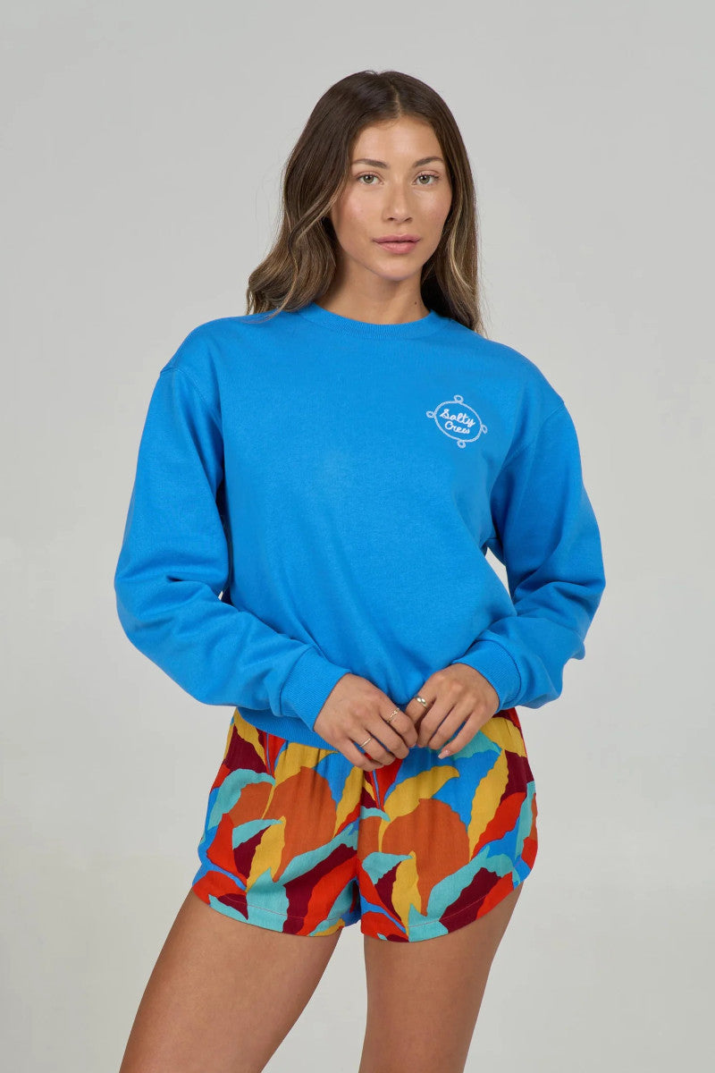 Woman wearing a blue sweatshirt and colorful shorts on a gray background