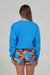 Back view of a person wearing a blue sweatshirt and colorful shorts on a plain background