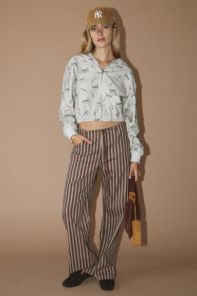 Woman wearing a duck patterned hoodie and striped pants against a beige background