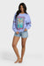 Woman wearing a light blue sweatshirt with a palm tree design and denim shorts on a white background