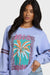 Woman wearing a light blue sweatshirt with a palm tree design and 'Bella' branding.