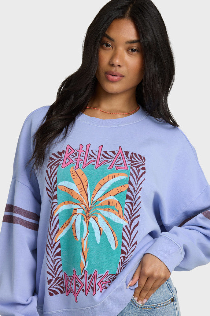 Woman wearing a light blue sweatshirt with a palm tree design and 'Bella' branding.