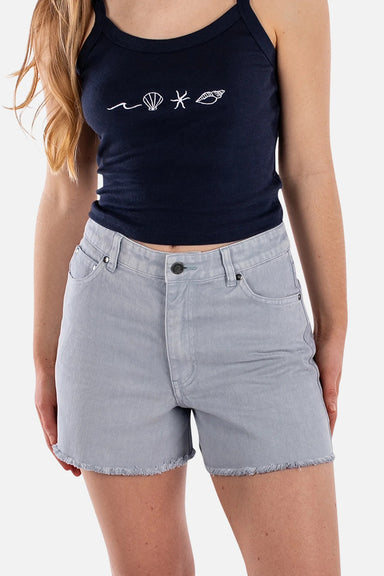 Woman wearing cutoff jean shorts and navy tank top on a white background