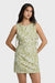 Woman wearing a green and white patterned dress with side ties on a white background
