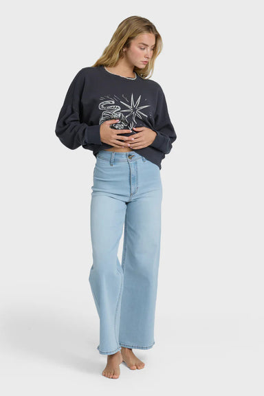 Person wearing a charcoal sweatshirt with a graphic design and light blue jeans on a white background