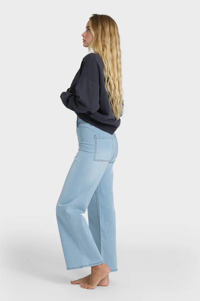 Woman wearing light blue jeans and a charcoal top on a white background