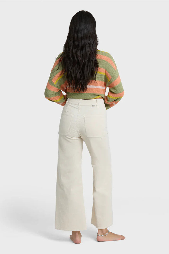Back view of a woman wearing a striped shirt and white pants on a white background