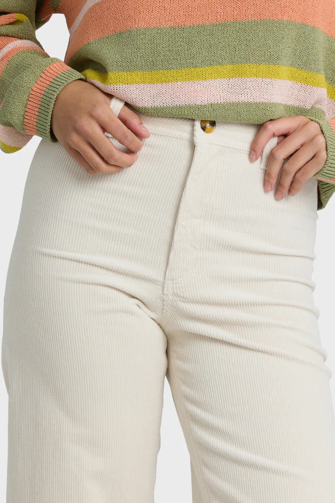 Person wearing a colorful striped sweater and beige pants on a white background