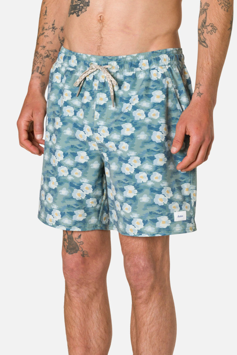 Man wearing blue floral shorts on a plain background