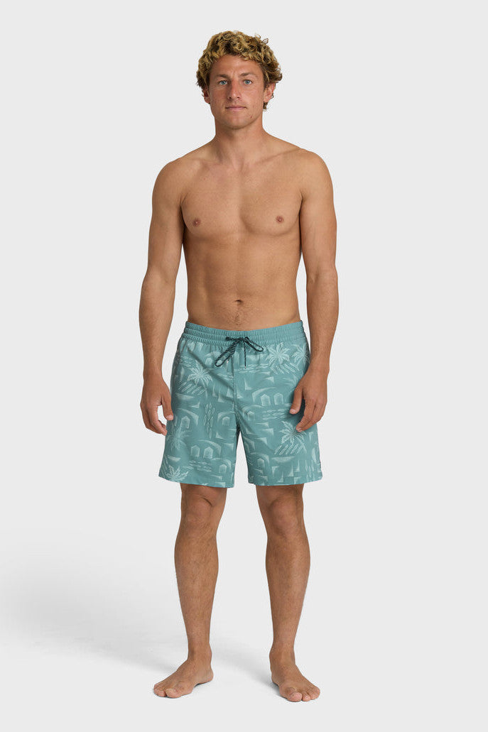 A man wearing teal boardshorts with a palm tree pattern, elastic waist and drawstring on a white background.
