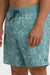 A man wearing teal boardshorts with a palm tree pattern, elastic waist and drawstring on a white background.
