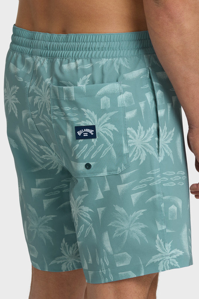 A man wearing teal boardshorts with a palm tree pattern, elastic waist and drawstring on a white background.