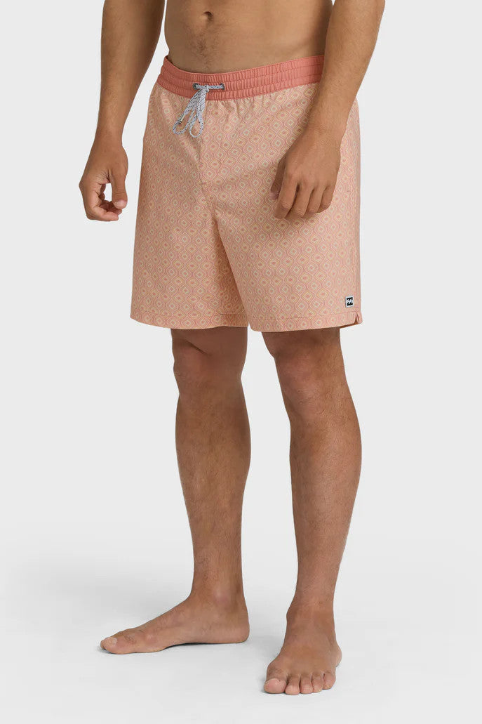A man wearing peach-colored boardshorts with a tonal pattern, elastic waist and drawstring on a white background.