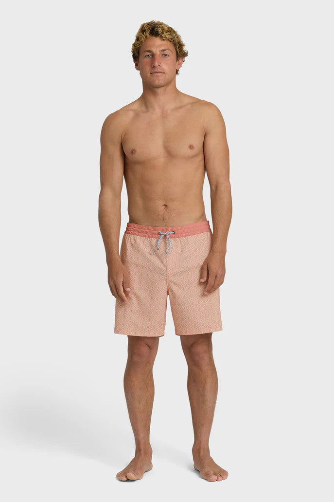 A man wearing peach-colored boardshorts with a tonal pattern, elastic waist and drawstring on a white background.