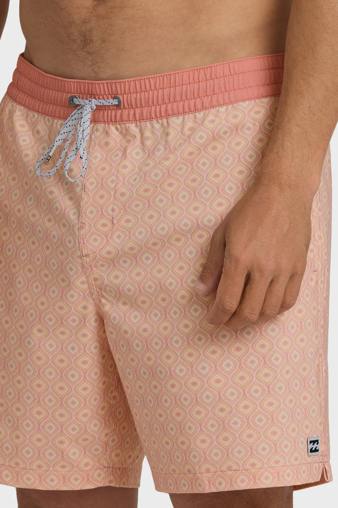 A man wearing peach-colored boardshorts with a tonal pattern, elastic waist and drawstring on a white background.